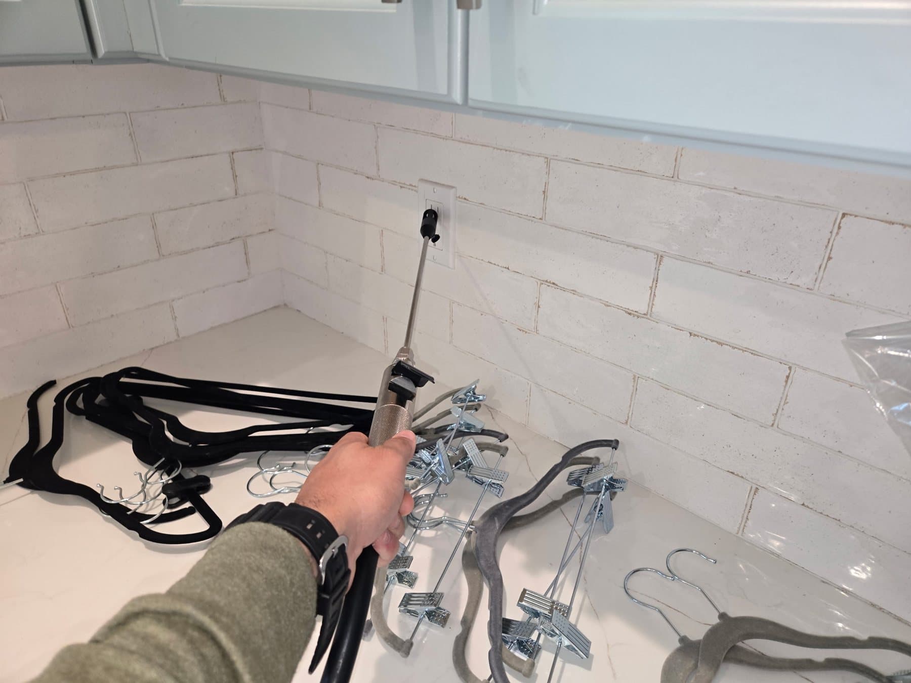 Inspector holding an air sampling wand at a wall outlet above a kitchen counter
